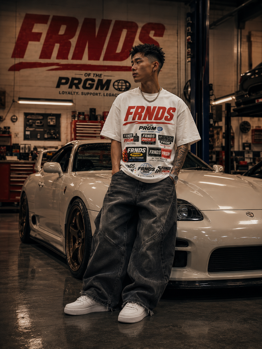 Model wearing the white FRNDS PRGM racing tee inside a custom auto shop