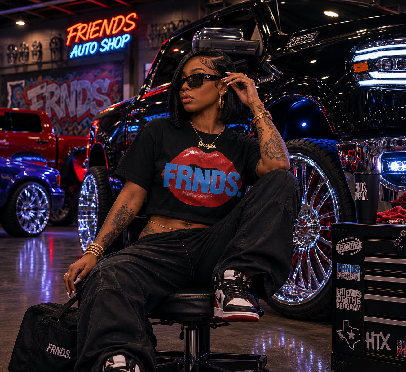 Model wearing the black FRNDS lips crop top in a custom auto shop scene